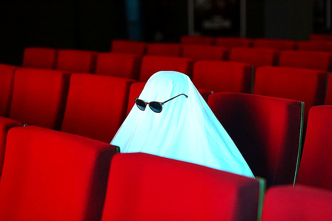 a ghost sitting in the middle of a row of red seats