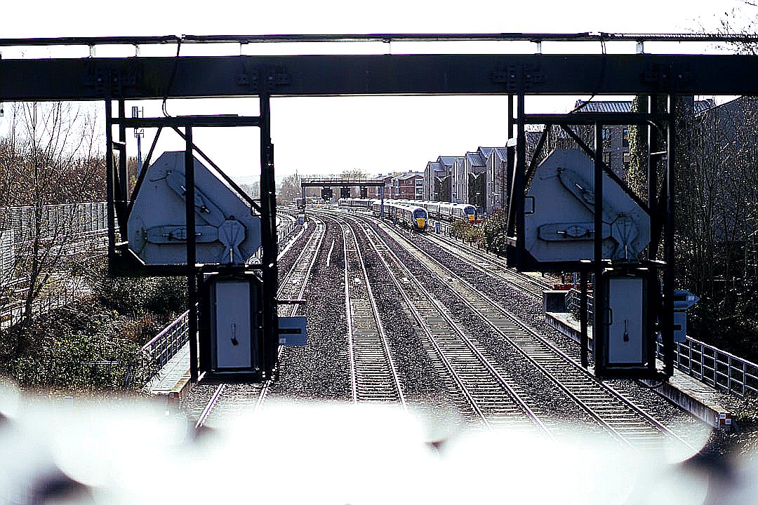 Train tracks leading into a city with overhead signals