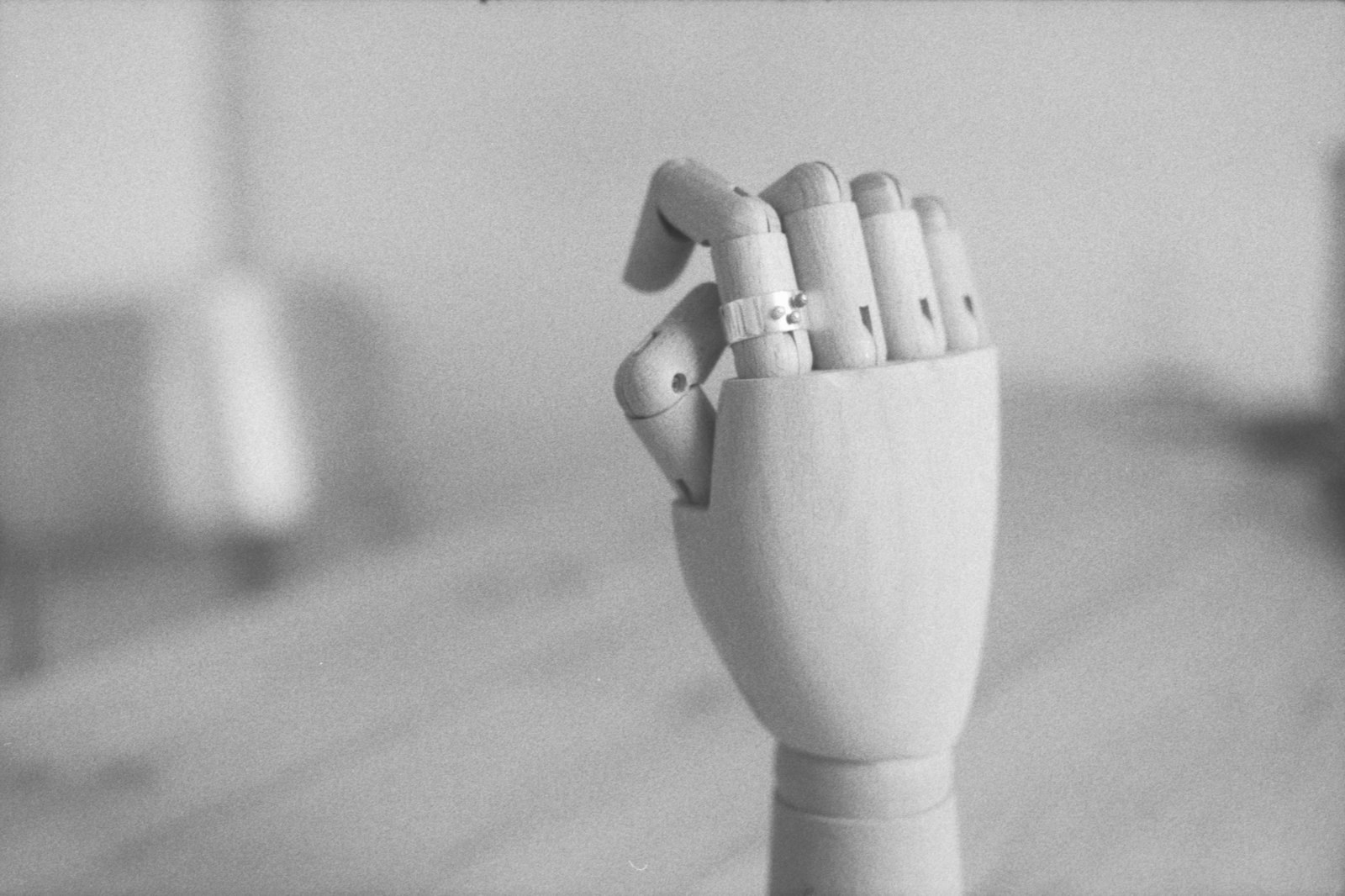 A wooden mannequin hand wearing a silver ring on its index finger