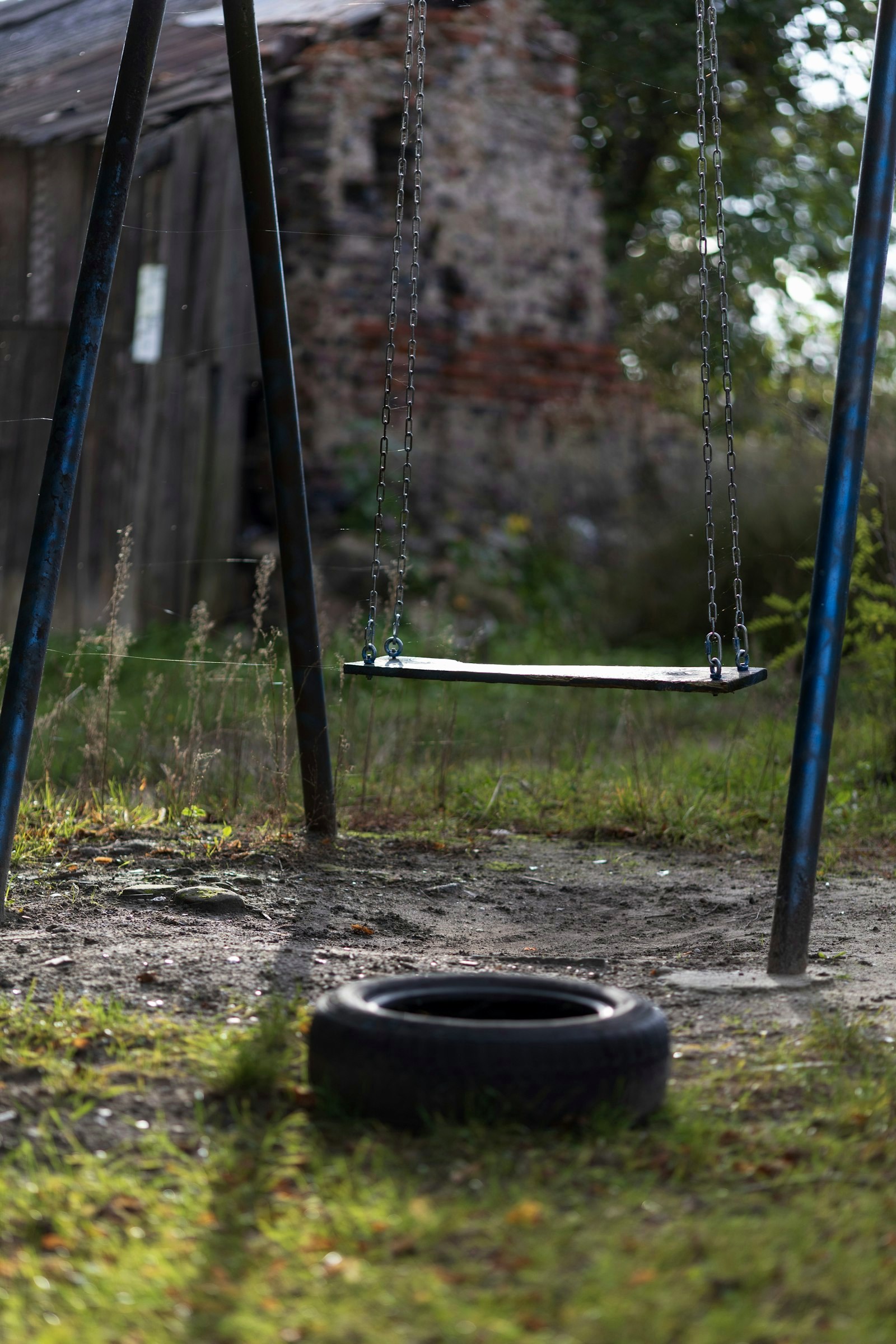 A tire sitting on the ground next to a swing set