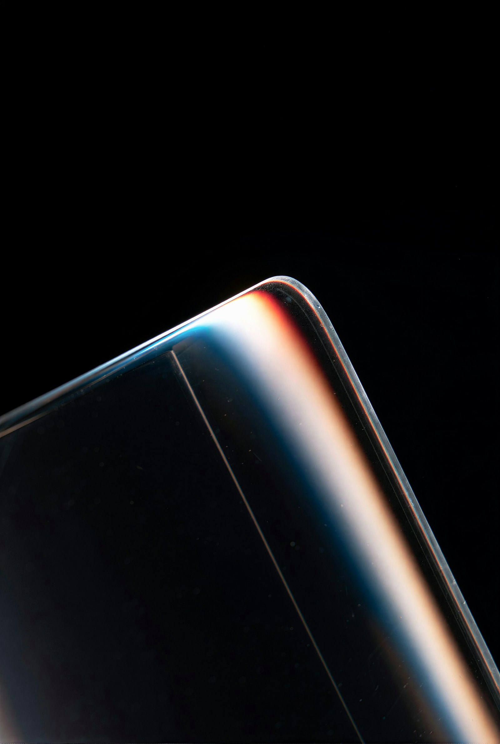Close-up of a curved glass edge with colorful light reflections