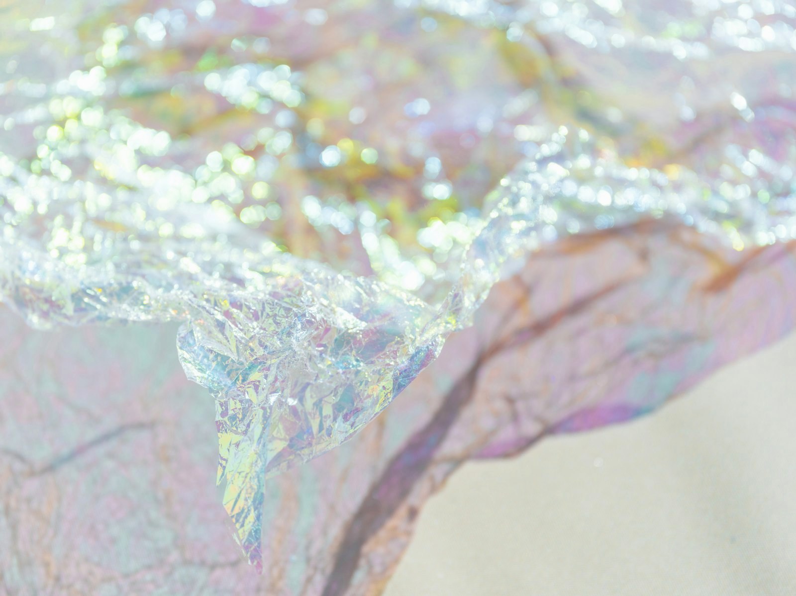 Crumpled iridescent wrapping paper on a cloth surface with soft bokeh highlights