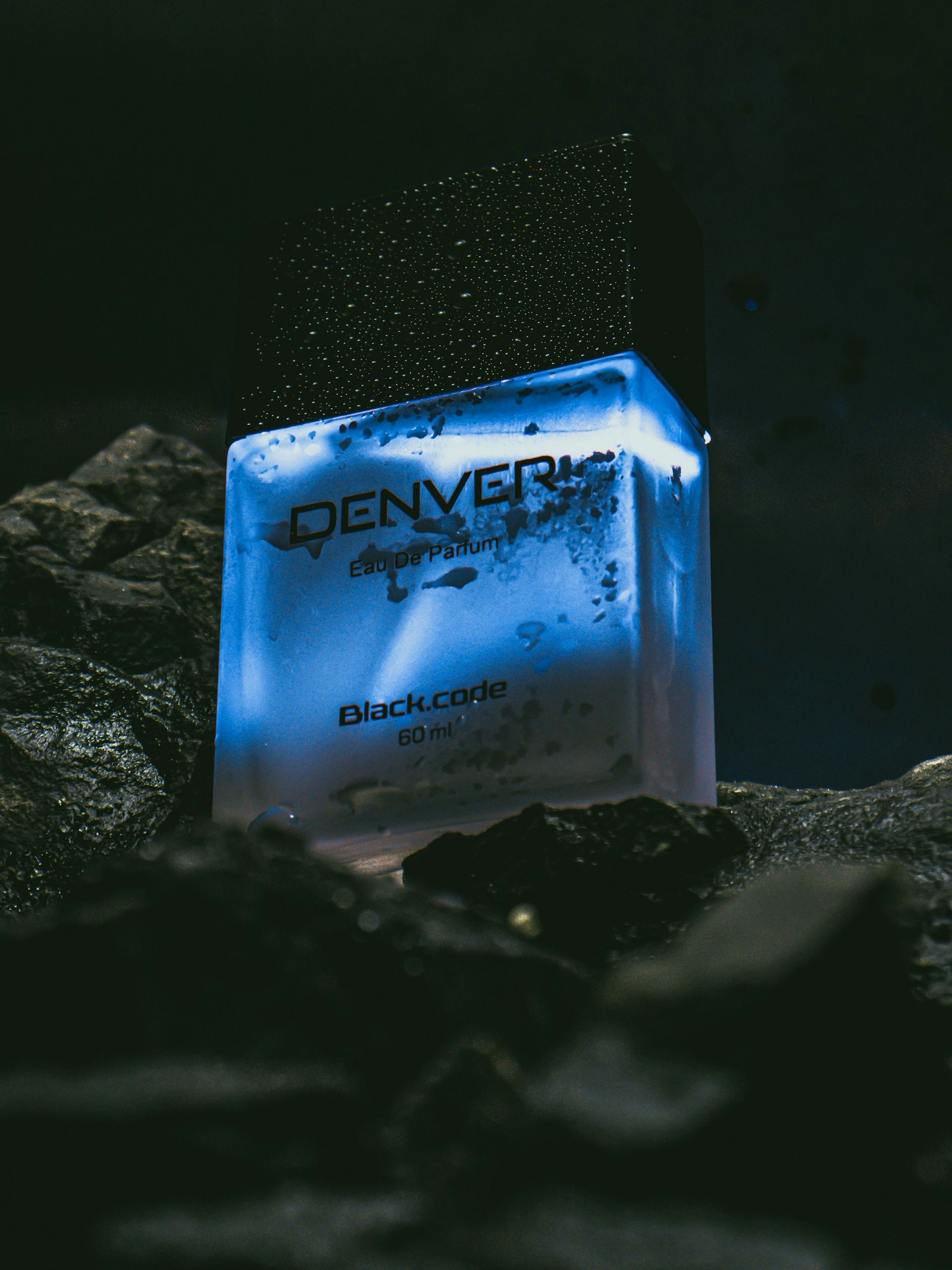 a bottle of denver cologne sitting on a rock